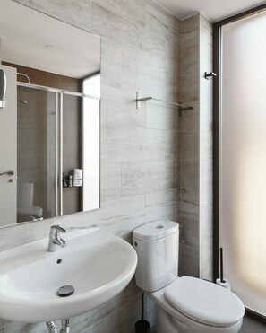 Ein modernes Badezimmer mit Waschbecken, Toilette und Duschkabine aus Glas.