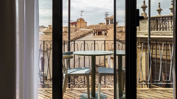 Un balcón con vistas a un paisaje urbano, con una mesa y sillas.