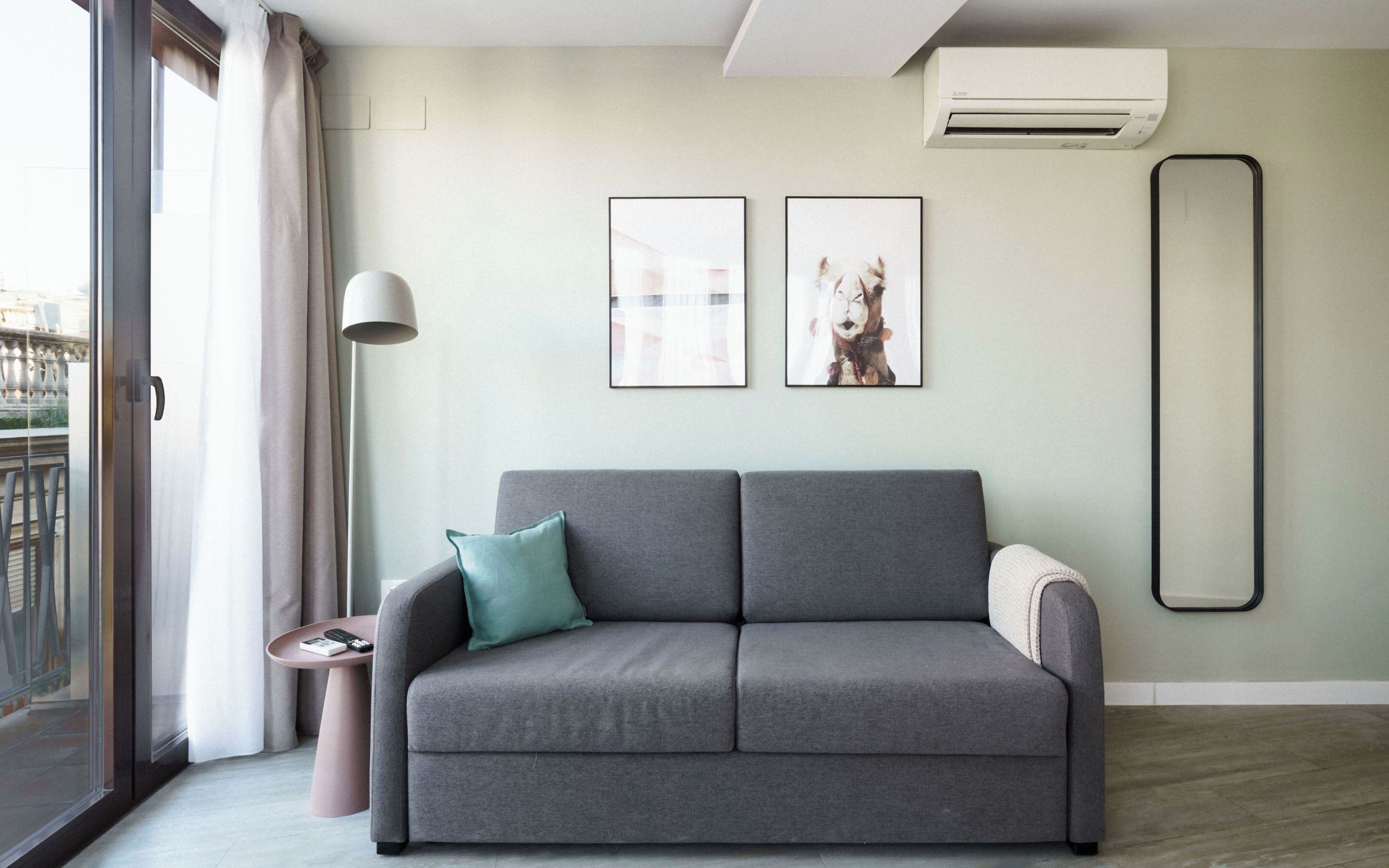 A modern living room with a grey sofa, a small side table, and two framed pictures on the wall.