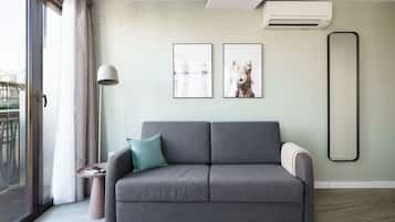 A modern living room with a grey sofa, a small side table, and two framed pictures on the wall.