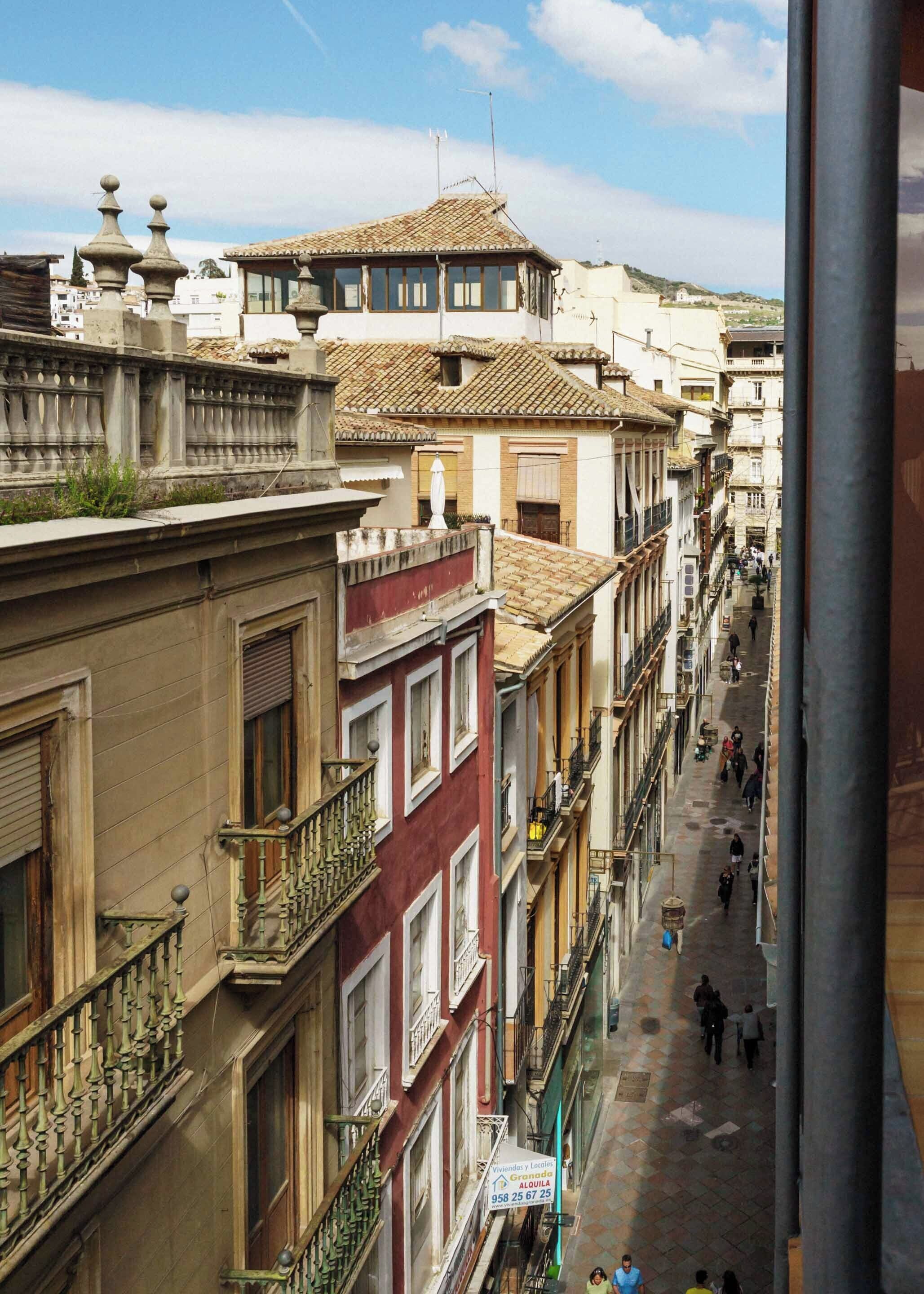 Une rue étroite bordée d’immeubles à plusieurs étages, dotés de balcons et présentant une architecture traditionnelle.