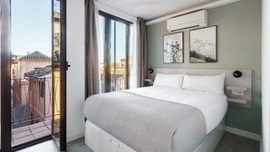 Una habitación de hotel con una cama grande, una puerta corrediza de vidrio a un balcón y dos cuadros en la pared.
