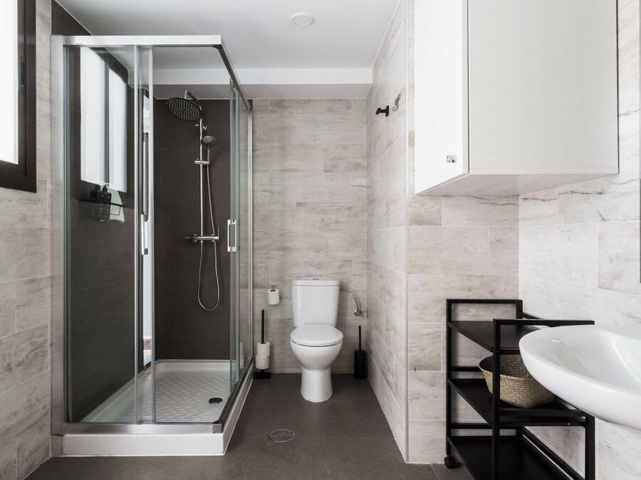 A modern bathroom with a glass-enclosed shower, a toilet, and a vanity with a sink.