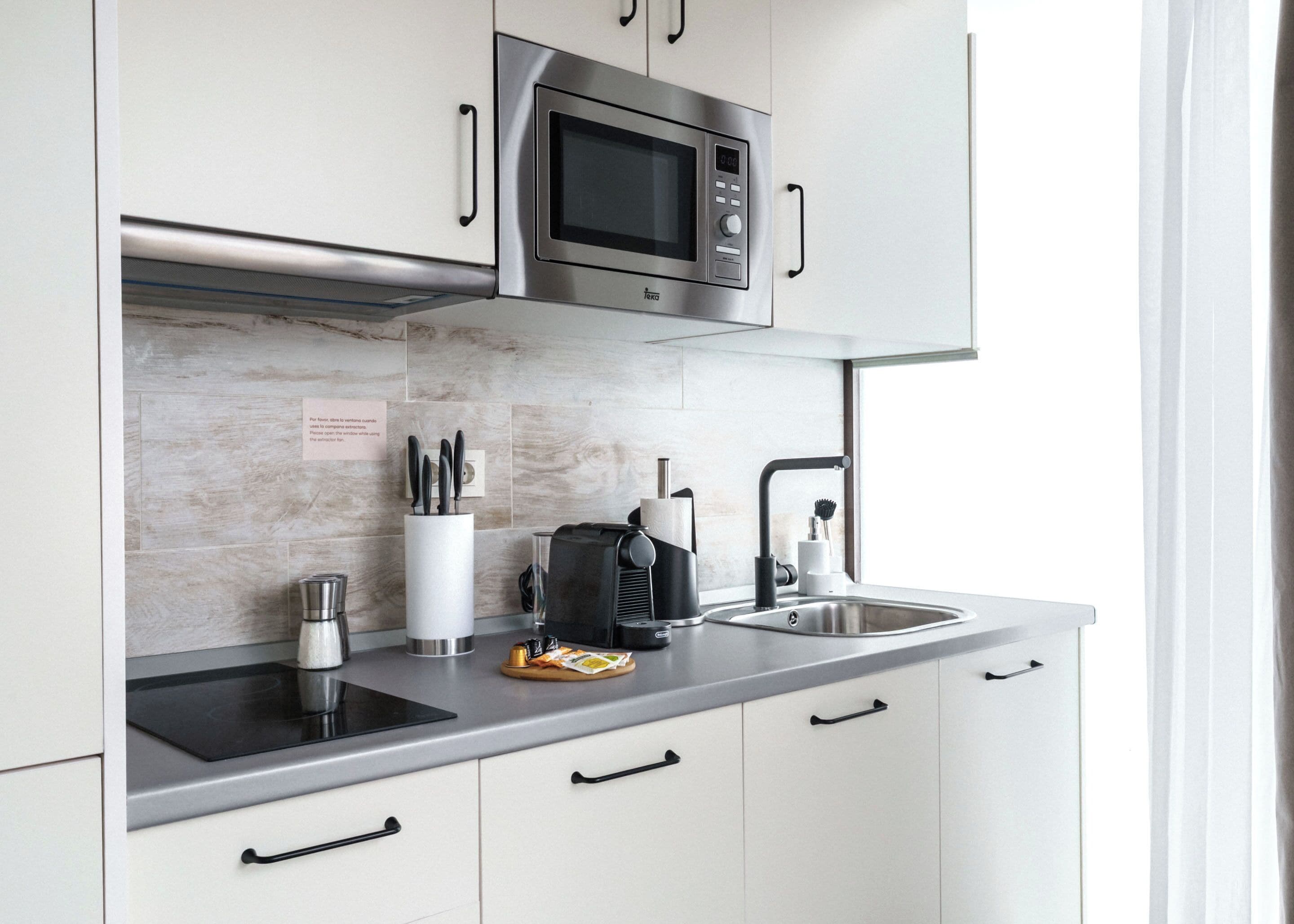 Una cocina moderna con un microondas de acero inoxidable, una cafetera y un lavamanos.