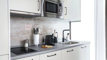 Una cocina moderna con un microondas de acero inoxidable, una cafetera y un lavamanos.
