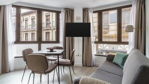 Una sala de estar moderna con sofá, mesa de comedor, sillas y televisor.