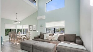 A spacious living area with a sectional sofa, ottomans, and a dining table with chairs. - Luxury Meets Coastal Charm in North Mission Beach (San Diego)