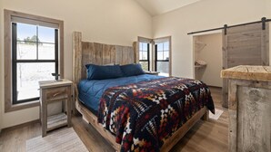 Une chambre à coucher avec un grand lit, une tête de lit en bois et un banc en bois rustique.