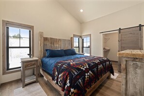 Une chambre à coucher avec un grand lit, une tête de lit en bois et un banc en bois rustique.