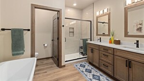 Une salle de bain moderne dotée d’une douche à l’italienne, d’une baignoire et d’un meuble-lavabo avec un grand miroir.