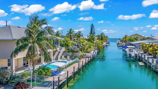 Un port de plaisance avec des bateaux amarrés, une piscine et un ciel bleu azur.