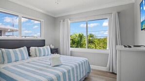 Une chambre à coucher avec un grand lit, une table de chevet, un bureau et une fenêtre avec des rideaux.