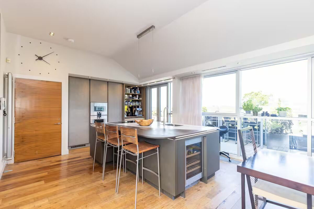 Una cocina moderna con una isla grande, taburetes de bar y un comedor con mesa y sillas.