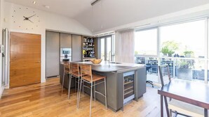 A modern kitchen with a large island, bar stools, and a dining area with a table and chairs.