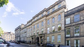 A historic building with multiple stories, large windows, and a prominent entrance with steps.