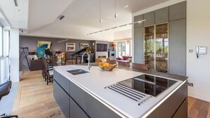 A modern kitchen with a large island, built-in appliances, and a dining area with a bar.