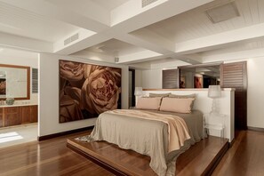 A bedroom with a large bed, a nightstand, a mirror, and a wall with a floral painting. - Oceanfront Retreat on Belmore (Sunshine Beach)
