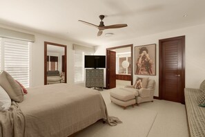 A bedroom with a bed, a chair, a dresser, a ceiling fan, and a large mirror.