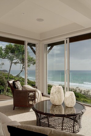 A modern living room with a large glass door leading to a balcony with a view of the ocean.