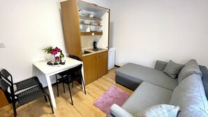 Un espacio habitable compacto con kitchenette, comedor y sofá.