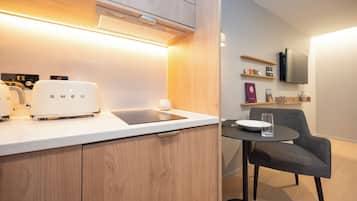 Una cocina moderna con un tostador empotrado, una tableta en la encimera y una silla junto a una mesa pequeña.