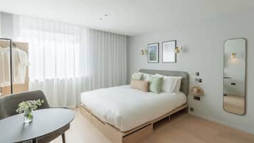 Un dormitorio moderno con cama, mesitas de noche, una silla y un espejo.