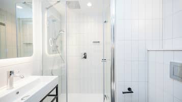 A modern bathroom with a glass-enclosed shower, a white sink, and a mirror.