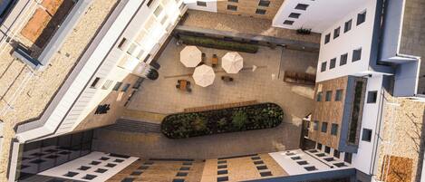 An aerial view of a modern building with a courtyard, outdoor seating area, and a unique architectural design.