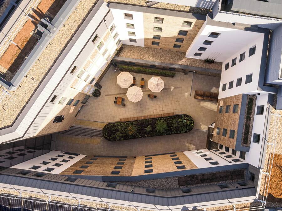 Vista aérea de um edifício moderno com pátio, área de estar externa e design arquitetônico único.