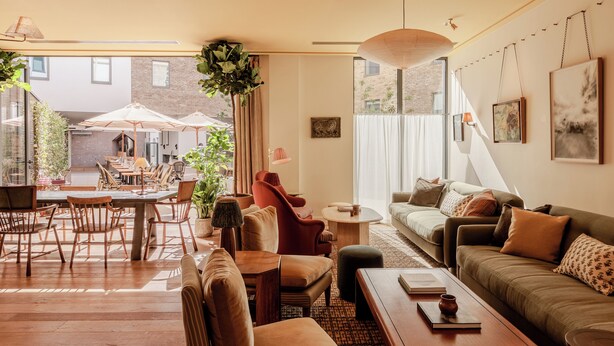 Een ruime woonkamer met een eethoek, grote ramen en uitzicht op het omliggende landschap.