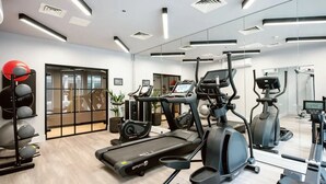 Een moderne sportschool met cardio-apparatuur, gewichten en een grote spiegel.