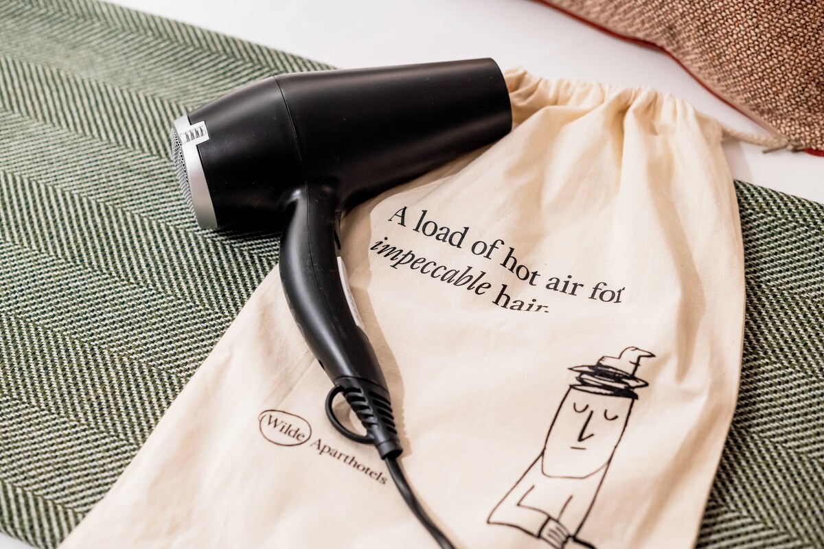 Un sèche-cheveux posé sur un tissu beige, avec du texte et un logo.
