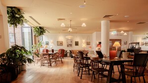 Een ruime hotellobby met houten vloeren, meerdere zithoeken en grote ramen voor natuurlijk licht.