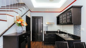 Una cocina moderna con armarios oscuros, encimera negra y una escalera de madera.