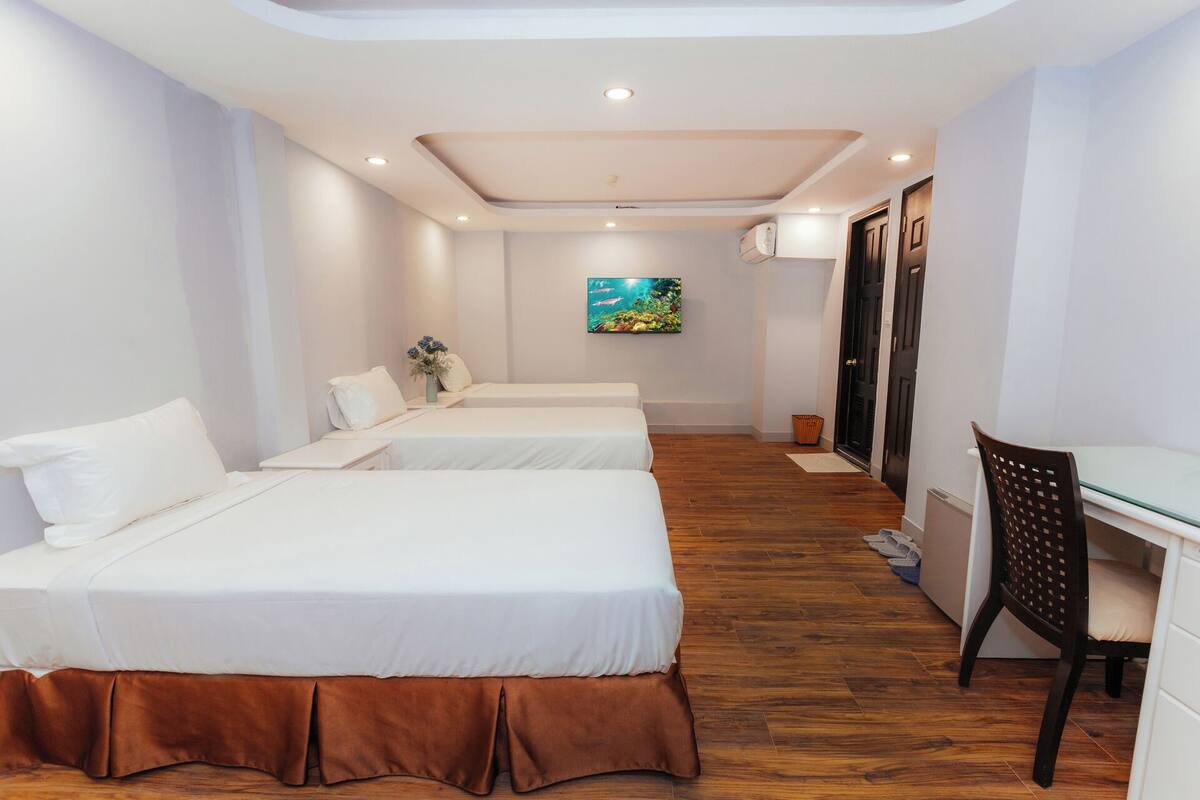 Quarto de hotel com duas camas, uma escrivaninha e uma cadeira.