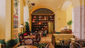 Ein gemütlicher Loungebereich mit Sitzgelegenheiten, einem Bücherregal und einer kleinen Pflanze.
