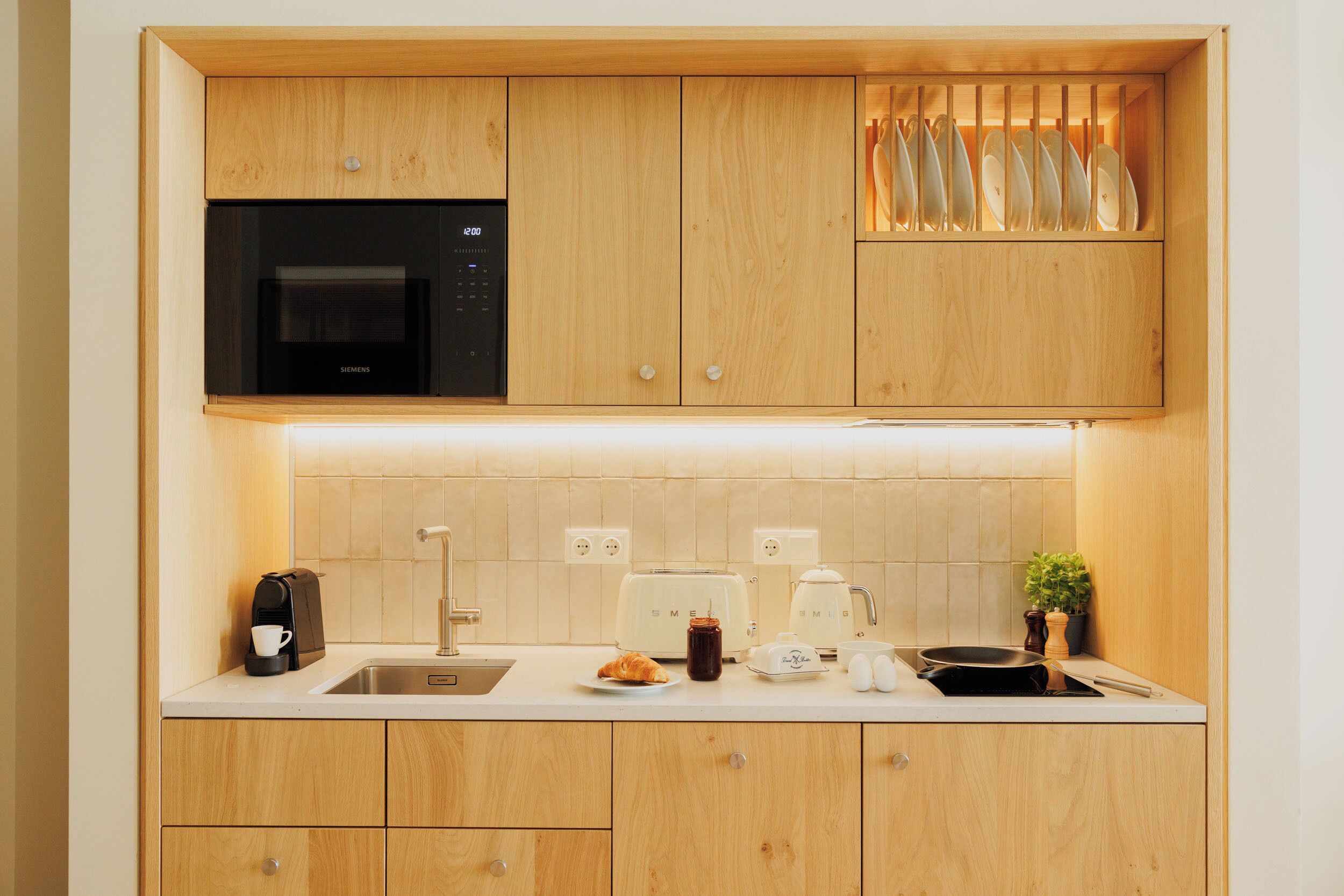 Eine moderne Küche mit Holzschränken, einer eingebauten Mikrowelle, einem Toaster und einem Spülbecken.