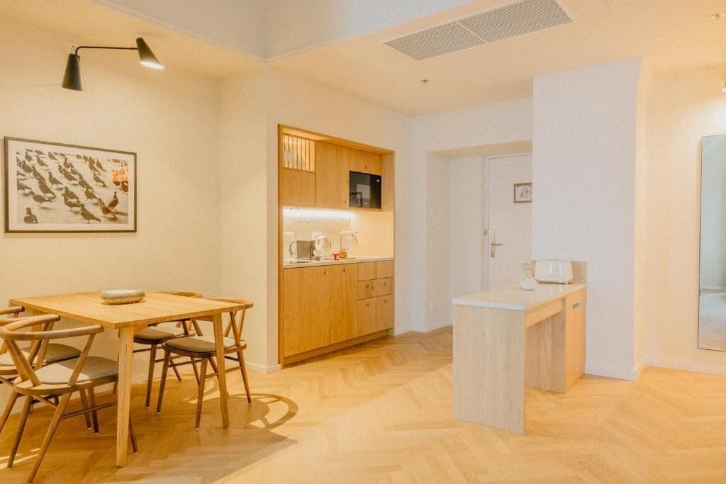 A compact kitchen with wooden cabinets, a dining table with chairs, and a small island.