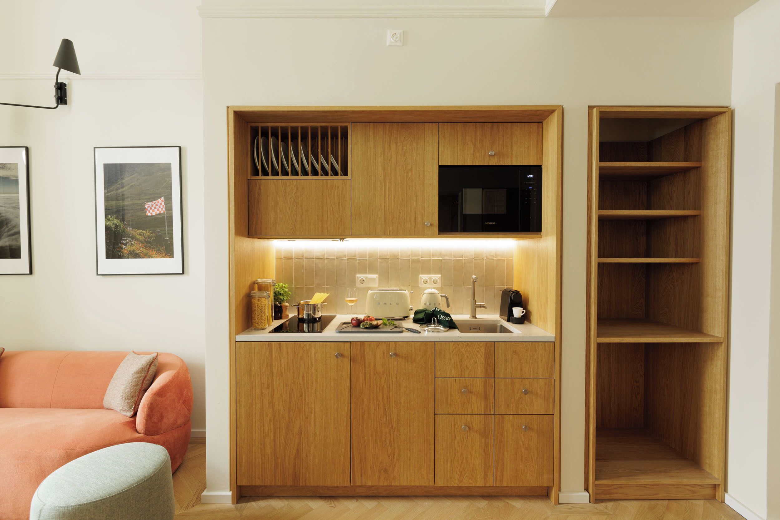 A compact kitchen with wooden cabinets, a microwave, and a built-in oven.