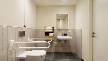 Ein modernes Badezimmer mit Toilette, Waschbecken, Spiegel und Handtuchhalter.
