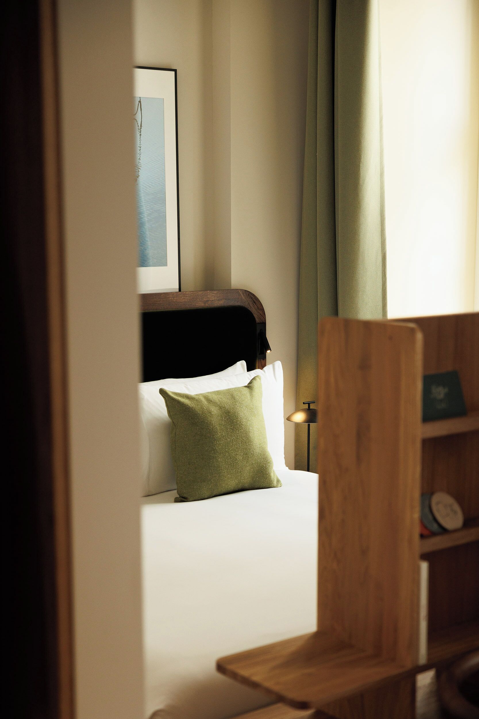 A hotel room with a bed, a nightstand, a lamp, and a wooden chair.