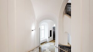 Ein langer, weißer Korridor mit einer Treppe, die zu einer Empore führt.