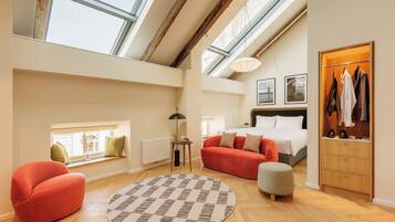 A spacious loft bedroom with skylights, a red sofa, a round rug, and a wooden wardrobe.