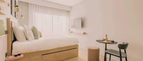 A modern bedroom with a bed, bedside table, and a small round table with a chair.