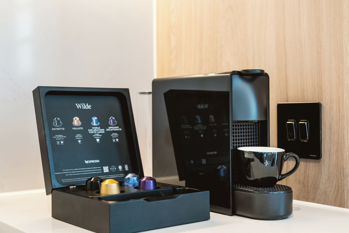 A coffee maker, a box of coffee pods, and a cup on a countertop.