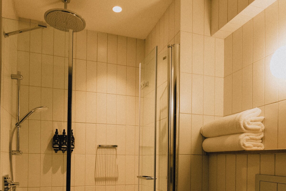 Ein Badezimmer mit einer gläsernen Duschkabine, Toilette und Handtuchhalter.