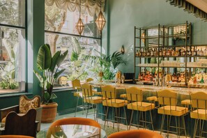 Un espace bar agrémenté d’un mur végétal, de nombreuses plantes, ainsi que de diverses bouteilles et verres disposés sur des étagères.