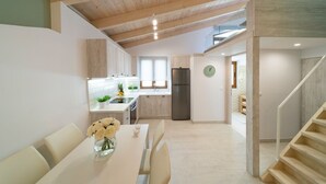 Eine moderne Küche mit Holzbalken, ein Essbereich mit Tisch und Stühlen sowie eine Treppe zu einer anderen Ebene.