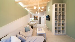 Ein modernes Interieur mit Holzbalkendecke, einem weißen Sofa mit gemusterten Kissen, einem kleinen Tisch und einer weißen Regaleinheit mit Pflanzen.