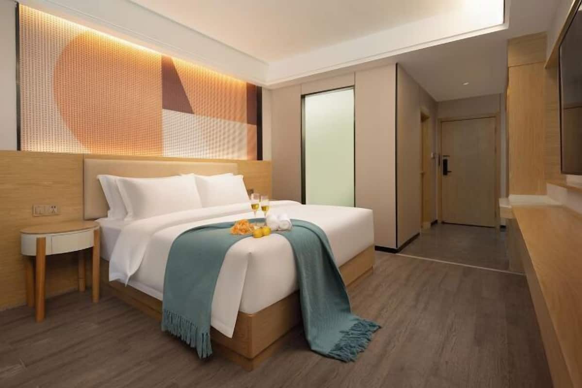 A modern hotel room with a bed, bedside table, and a large window.